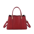 Bolso rojo con grabado de cocodrilo, asas redondas y correa ajustable sobre fondo blanco limpio - Burdeos