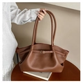 Detail of brown lychee grain leather tote bag with gold buckle on a wooden table - Brown