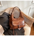 Vintage bruine tote bag van oliewasleer met groot voorvak op een rotan stoel geplaatst - Bruin