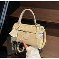 Dettaglio borsa beige intrecciata su gradino in legno con finiture in argento lucido - Bianco Sporco