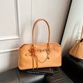 Sac bandoulière beige en cuir avec chaîne dorée et nœud tressé sur un canapé - Avec Pendentif / Marron Jaune