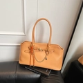 Orange leather baguette bag with heart charm and golden chain detail in a lifestyle setting - Yellowish Brown With Pendant