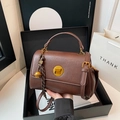 Brown matte leather messenger bag with gold twist lock and woven charm in a luxury setting - Red Brown