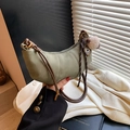 Green minimalist dumpling bag with knotted handle and plush charm shown in a lifestyle setting - With Pendant / Green