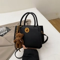 Schwarze Handtasche aus Leder mit goldener Schließe und süßem Bären-Anhänger-Detail - Schwarz