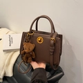 Braune Lederhandtasche mit goldenem Drehverschluss und einem niedlichen Plüschbär-Anhänger - Braun