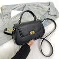 Détail d'un sac à main noir en cuir grainé avec fermoir pivotant doré et bandoulière - Noir