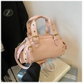 Borsa a mano rosa stile Boston con borchie dorate e tracolla regolabile su una valigia - Rosa