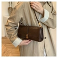 Detail of dark brown vintage leather shoulder bag with bronze clasp on khaki trench coat - Brown