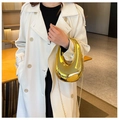 Detalle de un bolso de mano de acrílico espejo dorado con diseño curvo y minimalista - Dorado