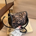 Leopard print PU leather crossbody bag with gold zipper displayed on a book - Leopard Print (Transparent)