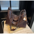 Detail of dark brown tote bag with contrast stitching and creative baseball charm on marble - Tan
