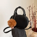Detail van de zwarte ovale handtas met matte textuur en bruine pompon-hanger - Zwart