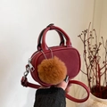 Detail van bordeauxrode mini-tas van leer en suède met bruine pluche pompon en handvat - Rood