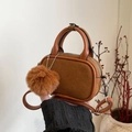 Detail van de bruine suède mini-handtas met stikseldetails en een zachte pluche pompon - Bruin