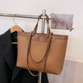 Detail of a brown lychee pattern leather tote bag with gold fashion lettering - Brown