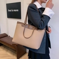 Detail of a large beige and brown leather tote bag with gold lettering shown on model - Khaki