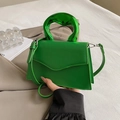 Detalle del bolso de cuero verde con asa metálica escultural y solapa de diseño moderno - Verde