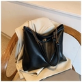 Detail of black tote bag with gold rotary lock and chain strap on a beige blazer - Black