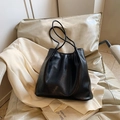 Minimalist black faux leather tote bag with fine texture on a soft white chair - Black