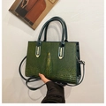 Dettaglio della trama coccodrillo verde scuro su un'elegante borsa quadrata con parti dorate - Verde