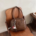 Retro brown leather handbag with baseball charm on a wooden chair, 2024 winter style - Brown with Pendant