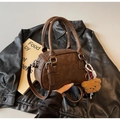 Dettaglio borsa Boston a cilindro marrone vintage con ciondolo a orsetto e manici - Marrone