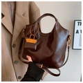 Detalle del bolso de cuero marrón oscuro con correa ajustable y mini amuleto - Burdeos