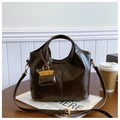 Bolso bandolera de cuero marrón vintage con mini colgante sobre mesa de madera - Marrón