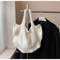 Weiße Stricktasche mit auffälligen Rüschenkanten an einem Kleiderbügel aus Metall - Gebrochenes Weiß