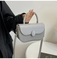 Close-up of light grey handbag with unique pleated texture and silver hardware details - Gray