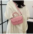 Pink crossbody bag with vertical stripe texture and metal buckle on a white trench coat - Pink