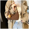 Sac à main croissant en daim marron avec breloque feuille tenu par un mannequin - Avec Pendentif / Marron