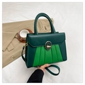 Détail du sac à main en cuir vert avec boucle ovale or et noir et poignée ronde - Vert