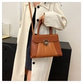 Sac à main marron à plis accordéon et fermoir doré porté avec un manteau blanc - Brun Foncé