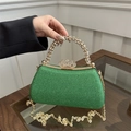 Macro view of emerald green sequin evening clutch with rhinestone crown clasp and handle - Green