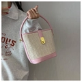 Pink and beige woven bucket bag with leather handles and gold clasp held by a model - Pink