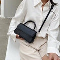 Bolso bandolera cuadrado minimalista negro combinado con camisa blanca y pantalón beige - Negro