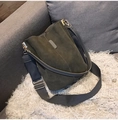 Olive green frosted leather bucket bag with gray fabric strap on white faux fur rug - Gray