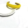 Macro detail of yellow beaded headband with sparkling sequins on a white ceramic plate - Yellow