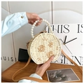 Detail of round woven straw bag with pearl handle and 3D floral embroidery accents - Beige