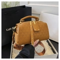 Close-up of brown embossed handbag with wide shoulder strap and gold hardware - Brown