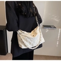 Weiße gesteppte Hobo-Tasche mit Kettenriemen getragen auf einem schwarzen Blazer - Weiß
