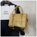 Detail shot of golden crocodile pattern texture and metallic clasp on the stylish handbag - Gold