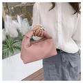Chic pink pleated handbag with knotted handle shown in a minimalist outdoor setting - Pink