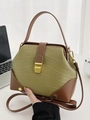 Detalle de bolso verde con textura de cocodrilo, ribete marrón y cierre metálico dorado - Verde