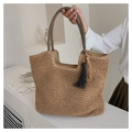 Détail d'un sac cabas en paille tressée avec anses rayées et pompons décoratifs sur le côté - Kaki