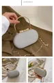 Macro view of silver sequin evening clutch bag with gold round handle and bow clasp - Silver