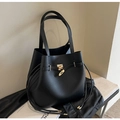 Klassische schwarze Ledertote mit goldenen Beschlägen und Riemendetails auf einer Bank - Schwarz
