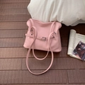Borsa tote minimalista in pelle rosa con fibbia argentata su sfondo in legno scuro - Rosa